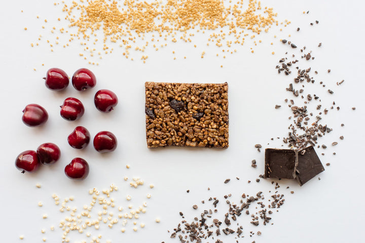 Dark Chocolate Cherry quinoa Hope bars with cherries, chocolate,, and quinoa in the background