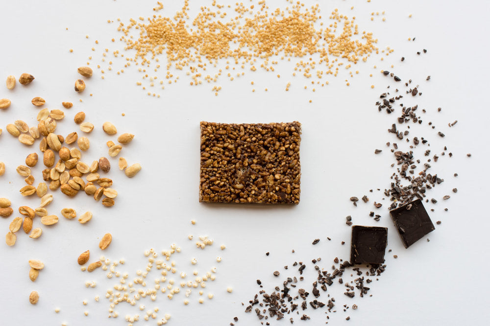 Peanut Butter Chocolate Quinoa bar with peanuts, chocolate, and quinoa in the background
